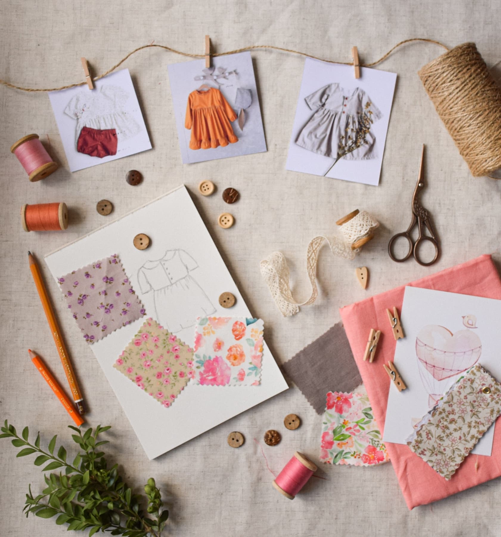 Sewing notions, fabric swatches, buttons and scissors laid out on a linen work surface